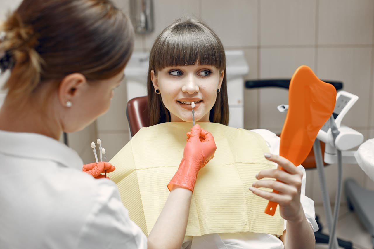 gallery-4 Dentist consults a young woman on veneers using dental tools and mirror in a clinic.